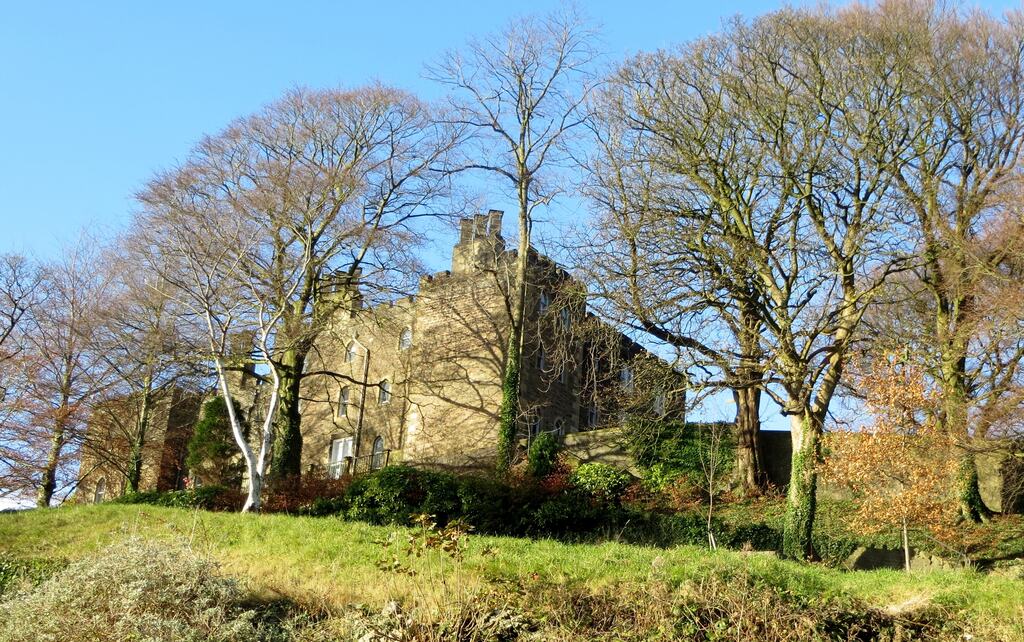 Clitheroe Castle keep on its limestone knoll above the town, with trees and grass in front